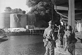 Příslušníci Commandos pozorují hořící nádrže s rybím tukem.