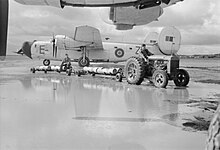 An RAF tractor, towing trolleyloads of depth-charges, negotiates a flooded disperal area between Consolidated Liberator GR Mark VIs of No. 220 Squadron RAF parked at Lagens. KG904 'ZZ-E' stands in the background Royal Air Force Coastal Command- No. 247 Group Operations in the Azores, 1943-1945. CA109.jpg