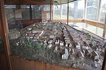 Una gran mesa encerrada en vidrio que contiene muchos edificios miniaturizados dispuestos para formar una ciudad.