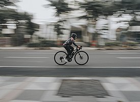 Seorang wanita sedang bersepeda dengan kencang di jalan raya