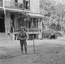 Men standing in front of building next to a small flag pole