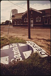 Abandoned Santa Fe depot sign in Halstead, 1974. Photo by Charles O'Rear. ABANDONED SANTA FE DEPOT SIGN WHICH ONCE BECKONED TRAVELERS AT HALSTEAD, KANSAS, NOW RUSTS IN WEEDS BEHIND THE... - NARA - 556013.jpg