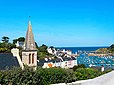 Vue de Sauzon à Belle-Île-en-Mer depuis la cours du presbytère. Au premier plan à gauche, on voit le clocher de l'église Saint-Nicolas de Sauzon, puis les maisons du quai Joseph Naudin et le port de Sauzon, avec le phare au fond.