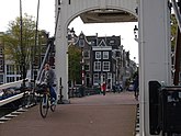 Biking over the Skinny Bridge (Magere Brug), over the Amstel river in Autumn; free photo Amsterdam by Fons Heijnsbroek, 10-2021