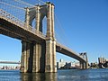 Brooklyn Bridge tower and cables in sunlight.