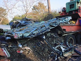 a blue 1990s Lincoln Town Car after crushing, with residue visible beneath Car exiting crusher.jpg