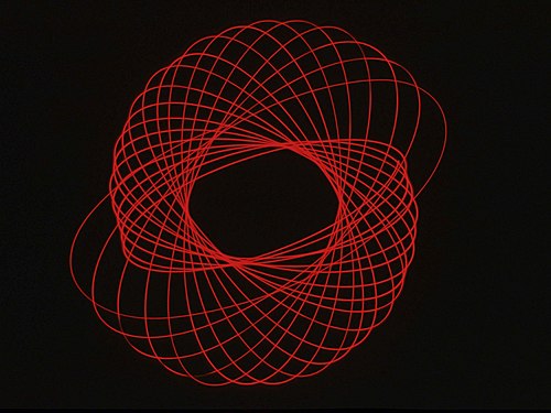 This is a long-term exposure shot of a flashlight with a bare bulb (no reflector) hanging on a hook from the ceiling and pushed to circle around. The camera was on a tripod facing upwards, using a red filter. Ca. 1978