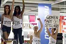 Neljä naista seisoo, rinnat puoliksi alasti, Ikea-myymälässä.