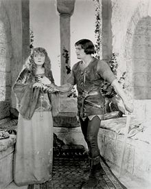 Douglas Fairbanks as Robin Hood giving Enid Bennett as Maid Marian a dagger Fairbanks Robin Hood giving Marian a dagger.jpg