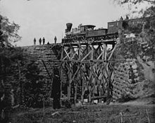 US Military Railroad engineers monitor the first use of a wooden trestle they have hastily built to replace the masonry bridge destroyed by Confederates, O&A railroad, Northern Virginia, c. 1863 Firefly train.JPG