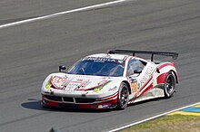 Foto de um carro branco e vermelho em uma pista de corrida.