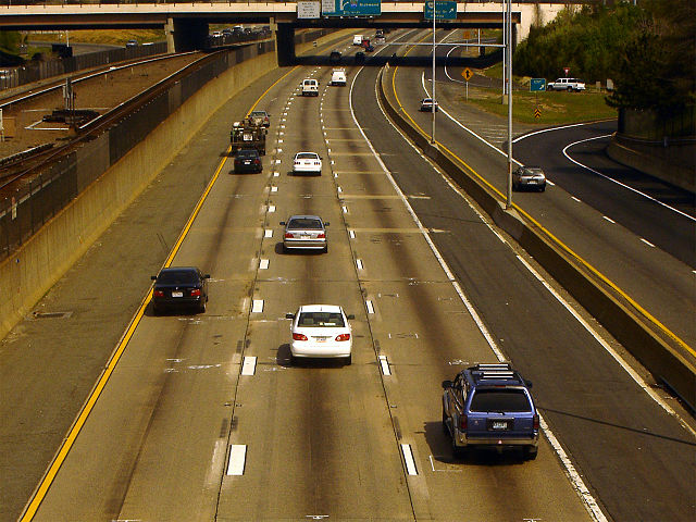 I-66 in Fairfax County with the Metrorail Orange Line in the median. The left lane is an HOV lane, and the right shoulder is used as a travel lane dur