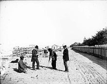 Klallam men in Sunday clothes on the beach, a Shaker church in the background Klallam men in western clothes on beach.jpg