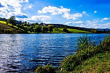 Danau dengan bergulir, bukit-bukit berhutan di seberang pantai