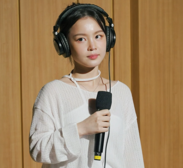 Lee Hi wears headphones and holds a microphone.