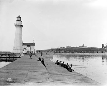 Fishing at Pierhead Light in Oswego, New York, c. 1900.  Fort Ontario behind.