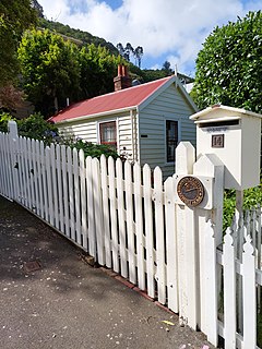 view of a cottage, its street fence, and a heritage plaque