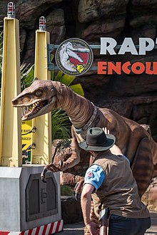 A velociraptor suit alongside a dinosaur "tamer" from Universal Studios Hollywood's "Raptor Encounter" attraction. Raptor Taming (28733062543).jpg