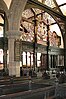 The interior of a church with an arch containing an elaborately carved screen in front of which are carved pews