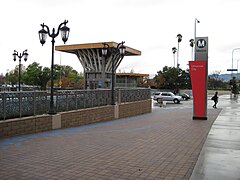 Buitenaanzicht van de stationslocatie.  In de verte kunnen we heuvels en palmbomen zien.  Grijze lucht.