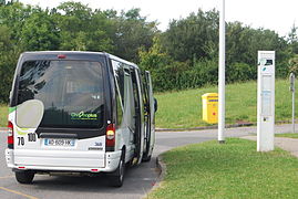 Hvit minibuss i utkanten av en rundkjøring.