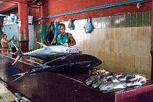 A fishmonger prepares to clean and butcher a pair of large fish in Male. A fishmonger prepares to clean and butcher a pair of large fish in Male.jpg