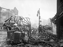A wrecked bus stands among a scene of devastation in the centre of Coventry after the major Luftwaffe air raid on the night of 14-15 November 1940. H5593.jpg