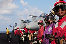 Yellow, brown, red and purple jersey colors on USS Dwight D. Eisenhower Flight deck crewmen watch as an F-A-18 Hornet launches from the flight deck of the aircraft carrier USS Dwight D. Eisenhower (CVN 69) as the ship conducts flight operations in the Arabian Sea on Nov 121125-N-NB538-105.jpg