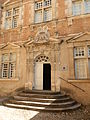 photo couleur d'une porte monumentale à pilastres et fronton orné d'un blason.