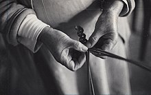 close up of hands plaiting together and open weave band. black and white photograph