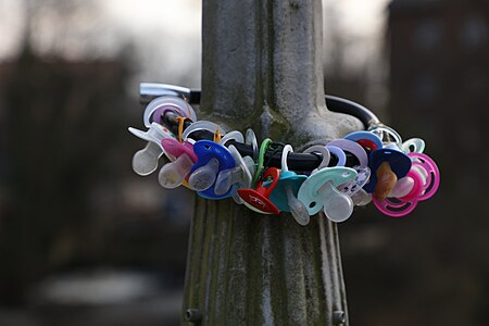 Assortment of pacifiers locked to a bridge over the Ilmenau river in Lüneburg