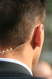 A bodyguard wearing an earpiece for two-way radio, so he can receive instructions. Personenschuetzer.jpg