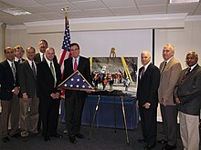 Senator Mark Warner feliciteert het Chileense Miners Rescue Support Team, inclusief Levine, terwijl hij een opgevouwen Amerikaanse vlag vasthoudt