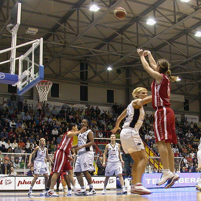 Een basketballer maakt een driepunter.