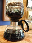 Step 7: The brewed coffee is finished, and located in the glass carafe. The glass coffee ground container contains grounds, which are drier (relative to filtered coffee grounds) due to the siphon also pushing air over the grounds.