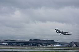 Boeing 777-300 von Air China beim Start, im Hintergrund ein Terminal