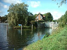 A lock cut on the River Thames at Bray Lock, Berkshire. The tall wooden poles are designed for boats to tie on to while awaiting entry into the lock. Bray Lock, Buckinghamshire.jpg