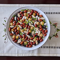 A colorful bowl of mixed dried fruits viewed from directly above, sitting on a flowered cloth