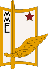 Прямоугольный белый герб, обрамленный золотом, с выпуклыми верхними и нижними краями, слегка несущим слева рукоять меча, помещенную внизу на раскрытом крыле справа, оба также из золота;  вверху слева расположены вертикально буквы M, M, F, L;  вверху справа красная звезда.