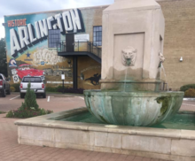 Replica of the historic mineral well in Downtown Arlington, in front of a mural. MuralWells.png