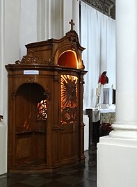 Un confessionnel en bois à Varsovie avec la lumière allumée, indiquant que le prêtre est à l'intérieur prêt à entendre des confessions