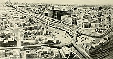 A 1913 illustration of the Queensboro Plaza station, showing the original four-story Queens Plaza Court Building and the Brewster Building. Queens Borough; being a descriptive and illustrated book of the borough of Queens, city of Greater New York, setting forth its many advantages and possibilities as a section wherein to live, to work (14779711391).jpg