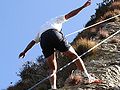 Climber being lowered by the belayer, with weight on the top rope and hands outstretched for balance while "walking" down.