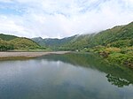 Ein breiter Fluss in einer grünen Berglandschaft.