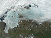 The frozen Laptev Sea. Thinning of the ice reveals blue and green water color. New Siberian Islands are near the middle and the Great Siberian Polynya is in the left part of the image.