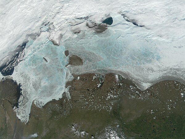 The frozen Laptev Sea. Thinning of the ice reveals blue and green water color. New Siberian Islands are near the middle and the Great Siberian Polynya