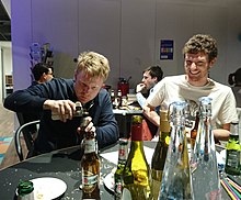 A person paying close visual attention to their use of a bottle opener, ignoring the other people around them Task Focus (cropped).jpg