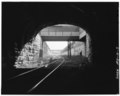 VIEW OF PEDESTRIAN CROSSING OVER TRACKS AT CAMDEN STATION LOOKING OUT FROM UNDER SOUTH PORTAL OF HOWARD STREET TUNNEL. - Baltimore and Ohio Railroad, Howard Street Tunnel, 1300 HAER MD,4-BALT,130-3.tif