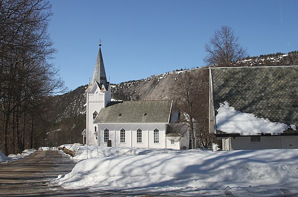 Åmli Church beneath a large mountainside