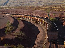 A long line of loaded iron ore wagons on a curve